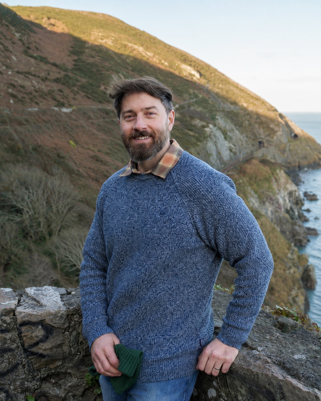 Adam Stamnos outdoors beside a coastal hillside
